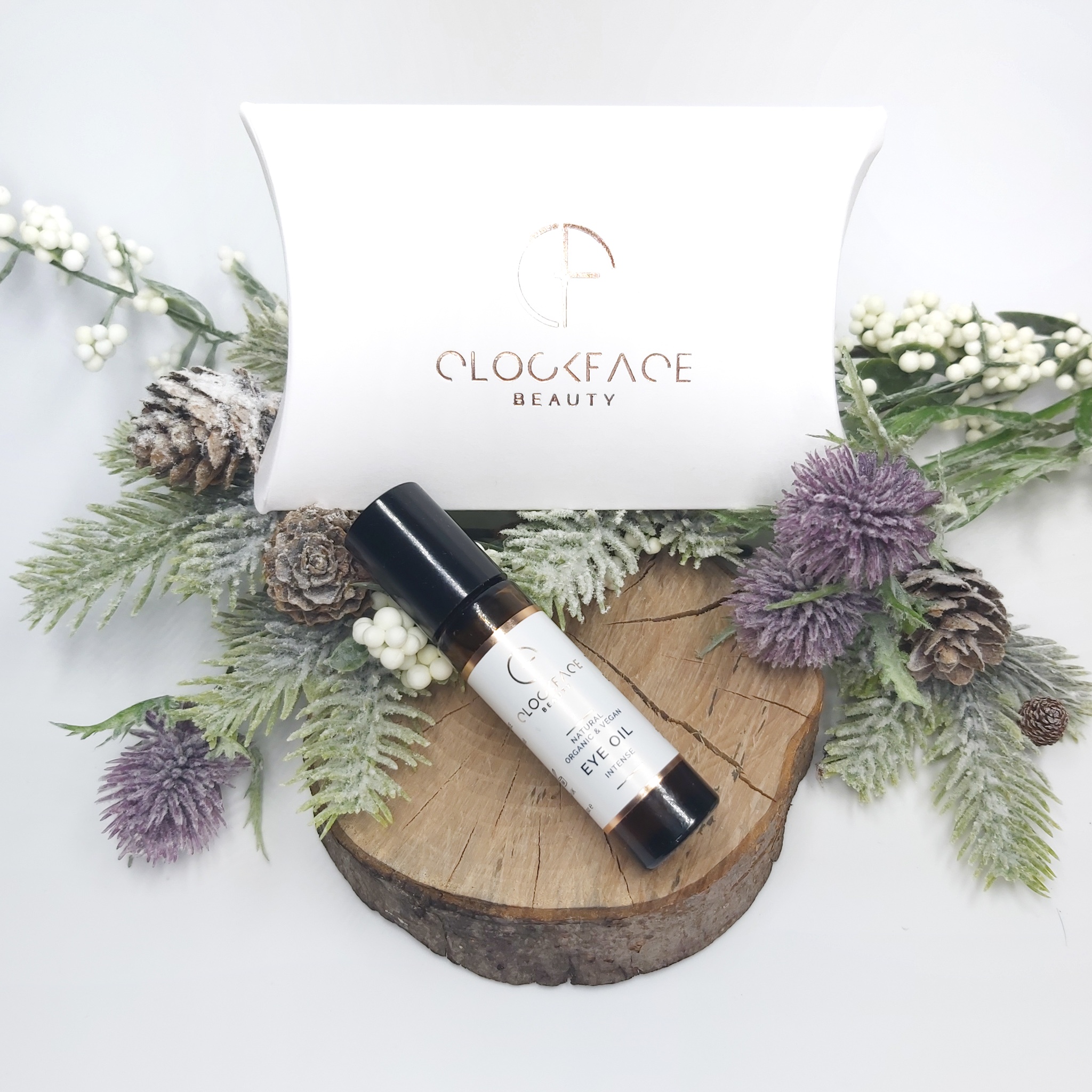 Clockface Beauty Intense Eye Oil on a log slice with the white pillowbox packaging. Natural Beauty Christmas Gift Guide by Beauty Folio